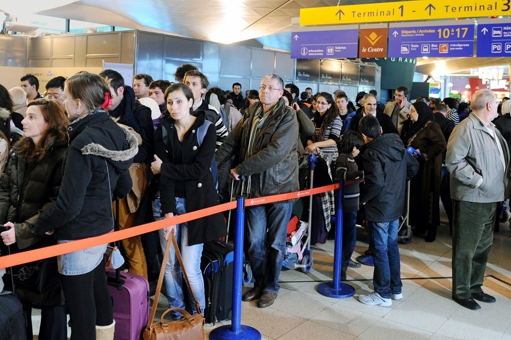 Passengers queue after flights have been cancelled as security officers
