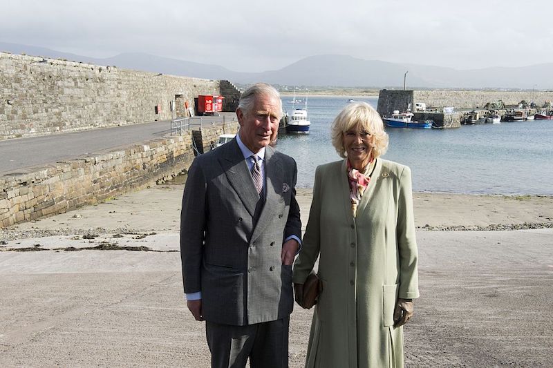 Prince Charles and Camilla Parker Bowles standing near a port.