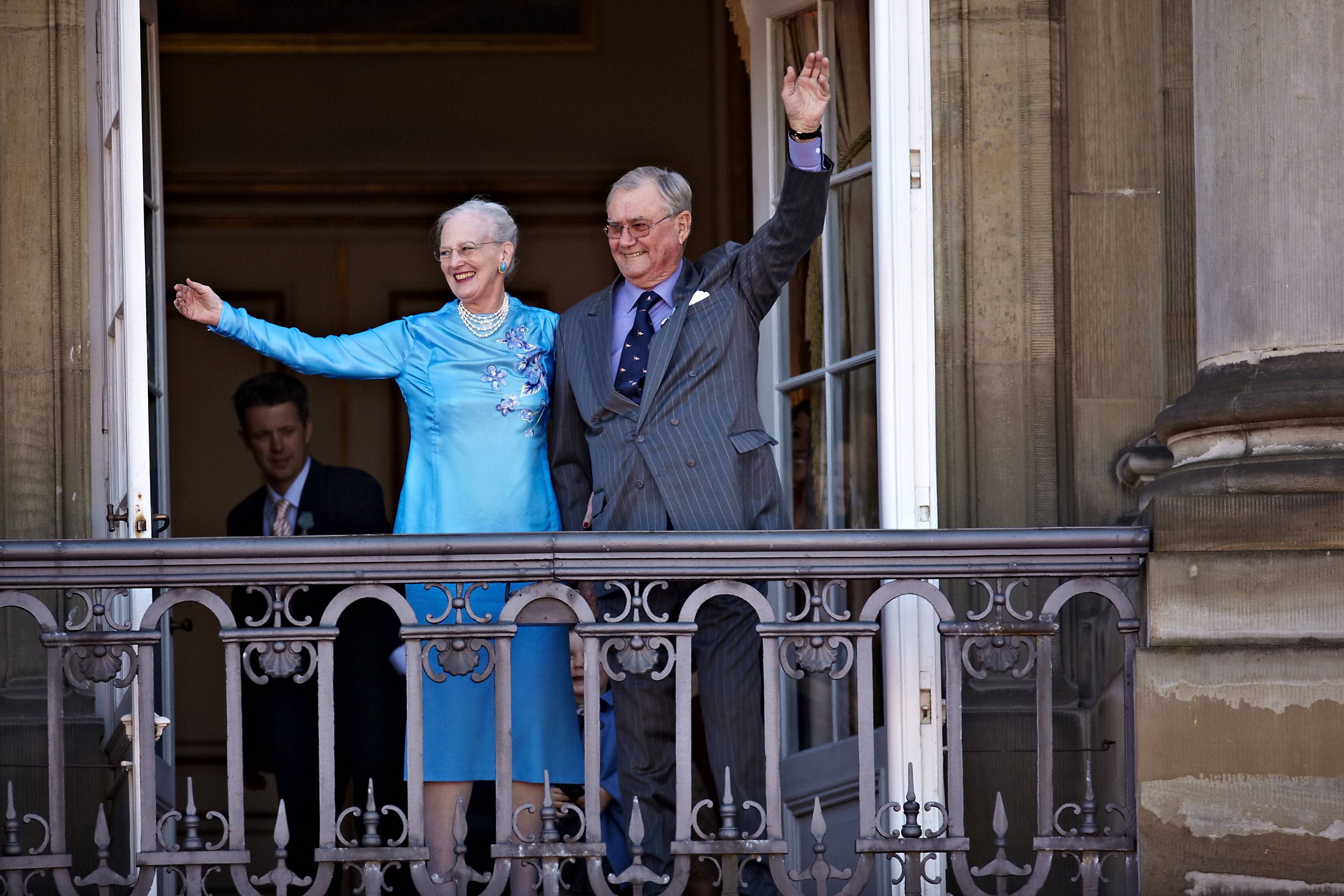 Queen Margrethe and Prince Henrik of Denmark waving from a balcony