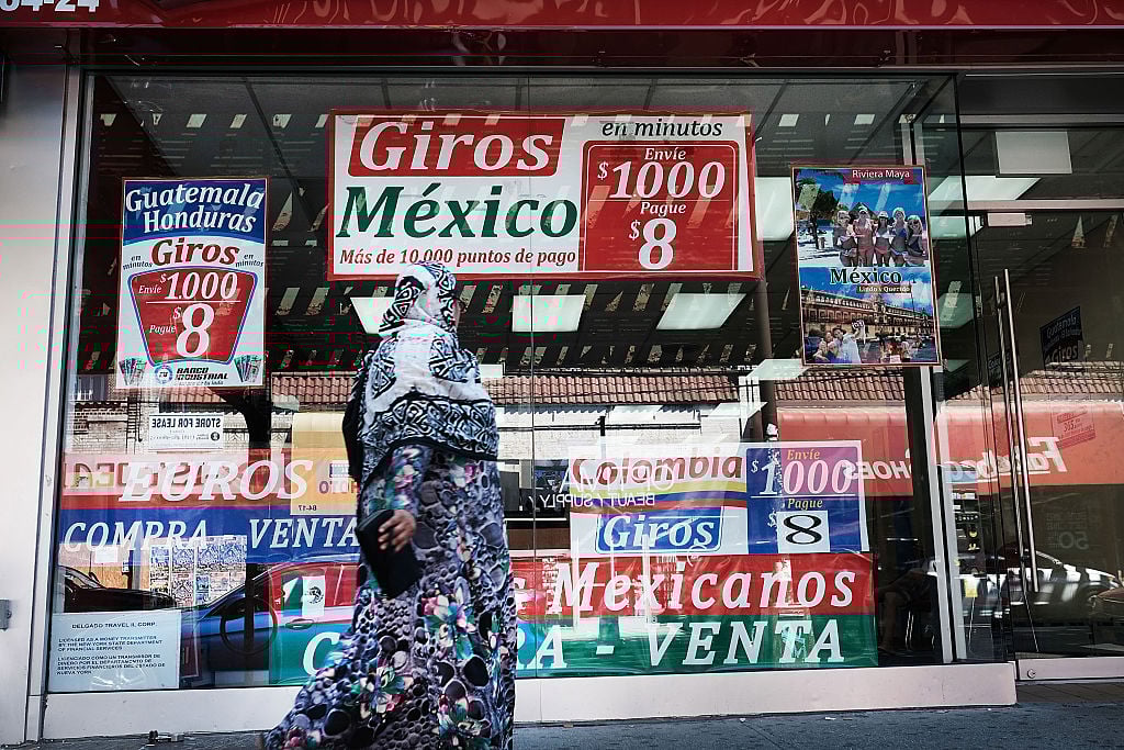 A woman walks by a store specializing in phone calls and travel to Latin America in the ethnically diverse neighborhood of Queens
