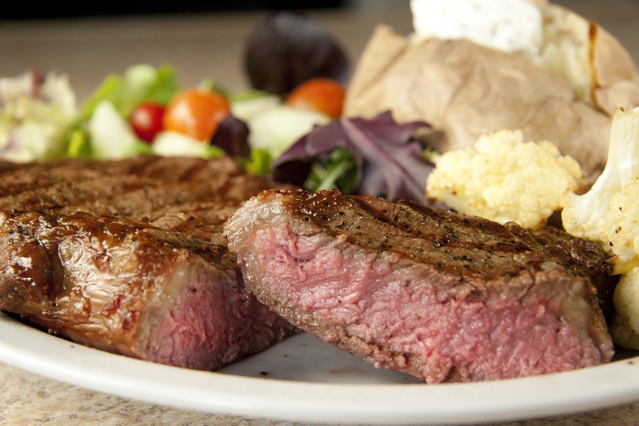Rib eye steak with baked potato and salad