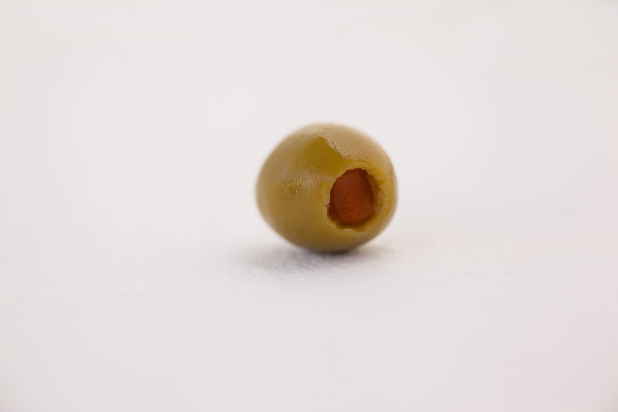 Single green olive on table