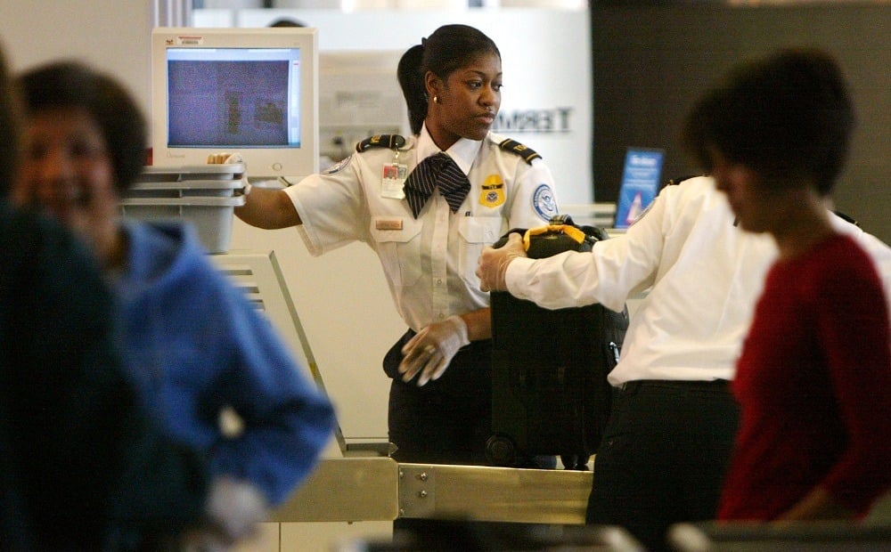 A Transportation Safety Administration (TSA) officer screens carry-on baggage at a passenger