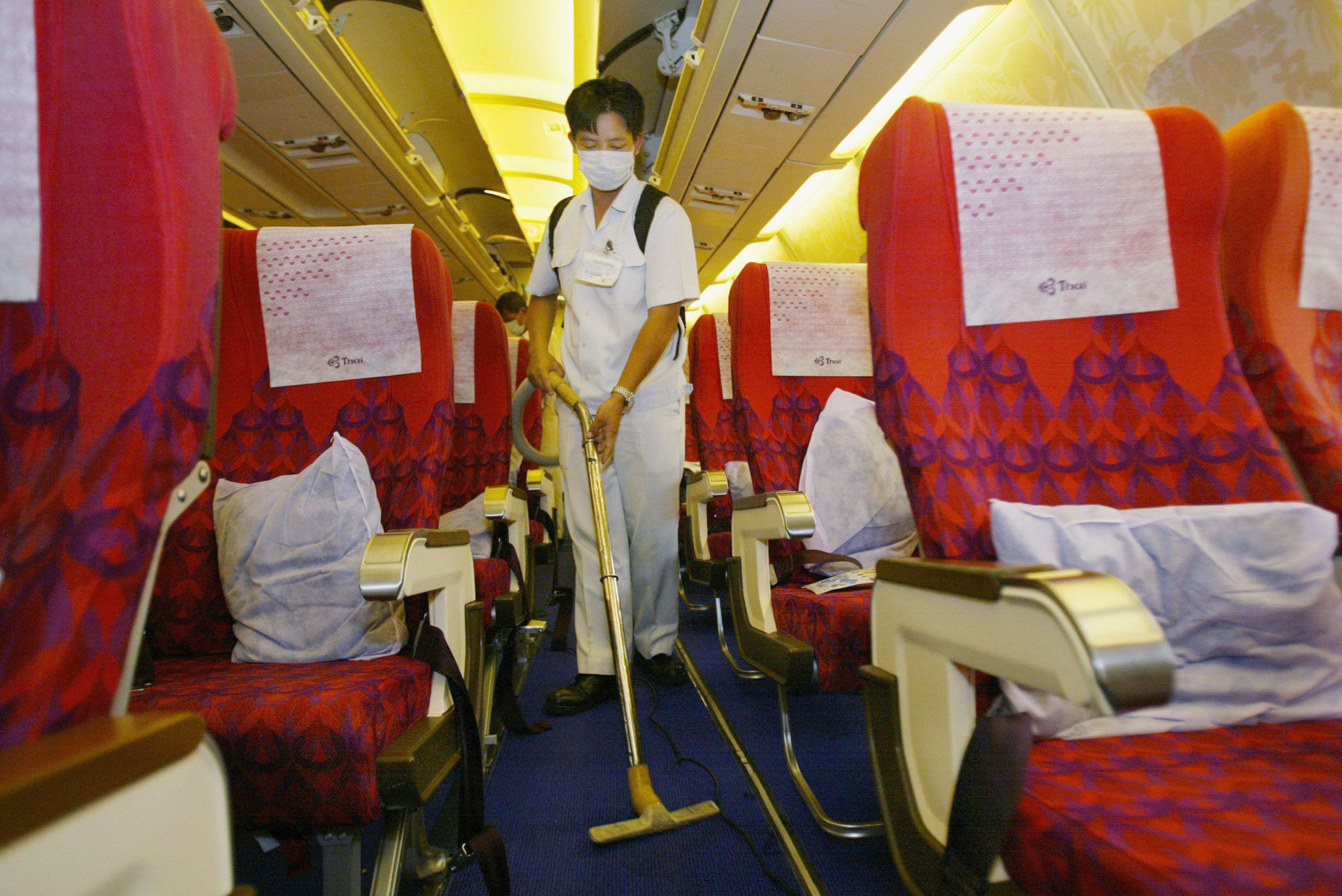 A Thai airlines staff worker cleans the aircraft wearing a surgical mask