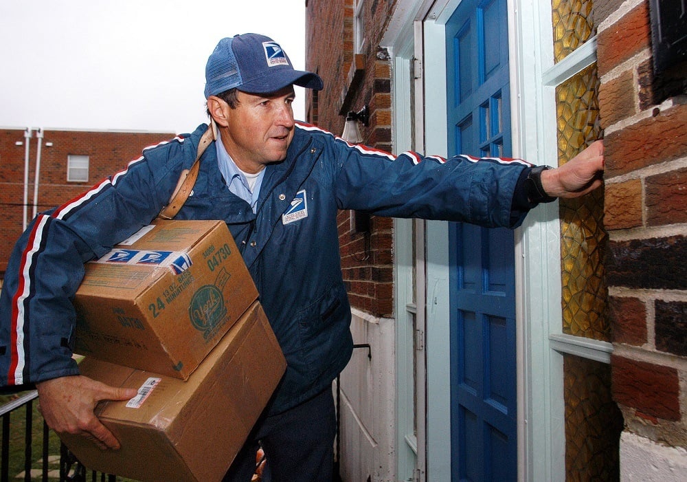 U.S. Postal Service carrier Ron Comly carries parcel packages