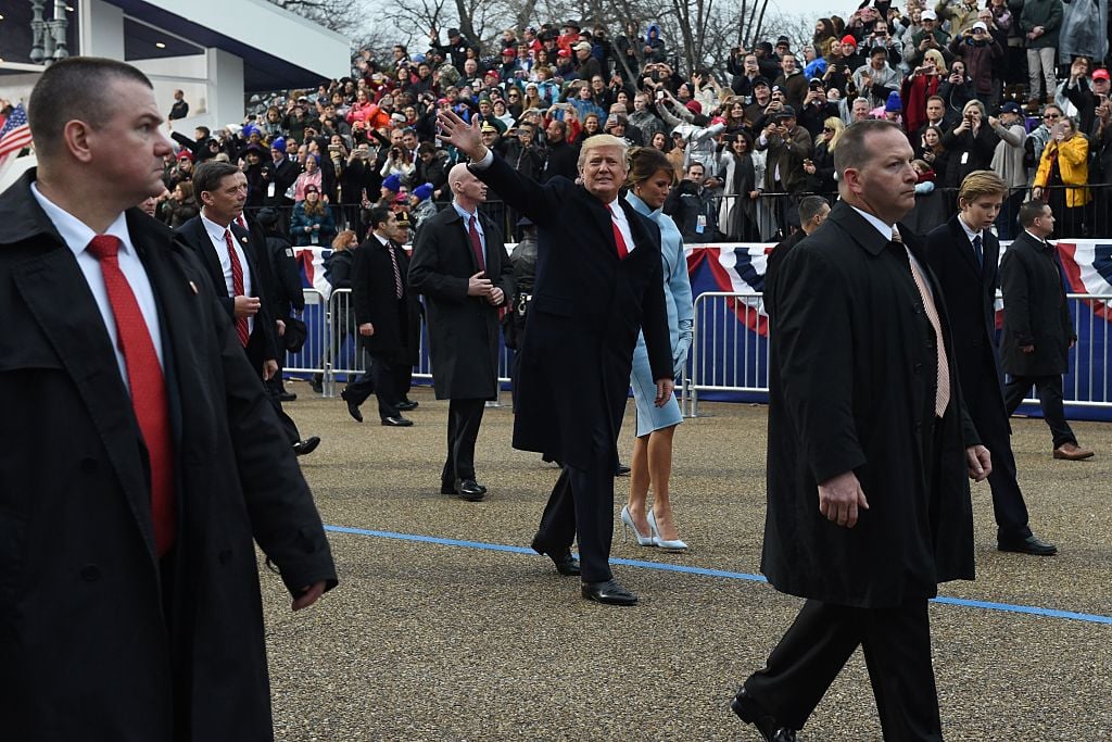 US President Donald Trump walks out of the car with his son Barron and wife Melania surrounded by Secret Service officers