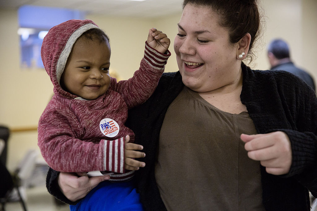 Hayley Bruneau receives a sticker after casting her vote with son Tayvin Faris, 1, at the Immaculate Conception Church on November 8, 2016, in Penacook, New Hampshire
