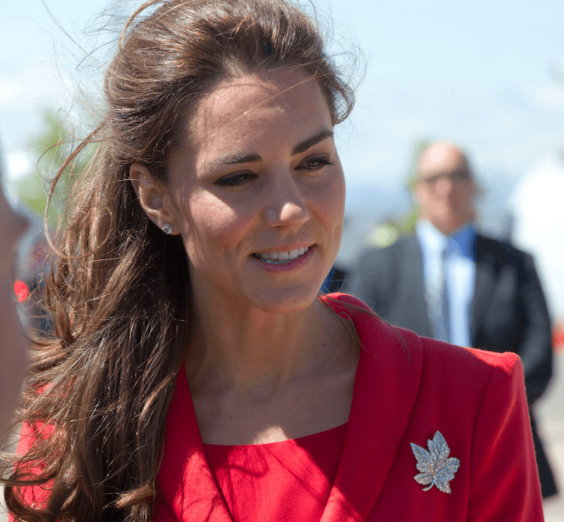 Kate Middleton wears a red dress with a brooch