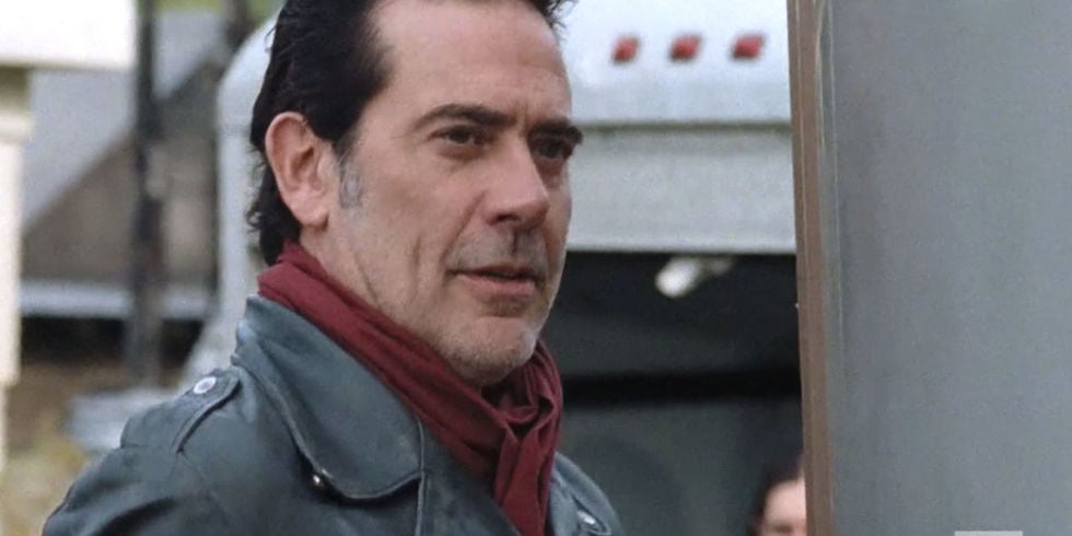 Negan looks ahead while wearing a black jacket and red scarf Negan looks ahead while wearing a black jacket and red scarf