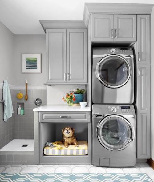 A dog sitting near a washing machine in a bed. A dog sitting near a washing machine in a bed.