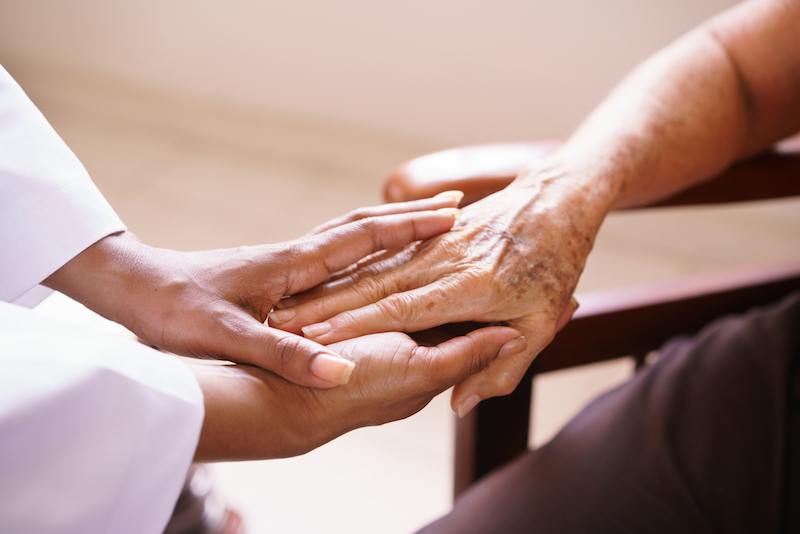 A doctor holding a senior's hand