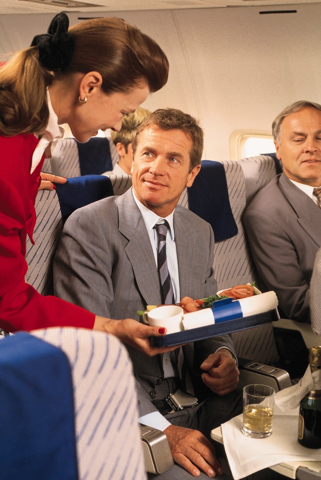 Flight attendant helping businessman on airplane
