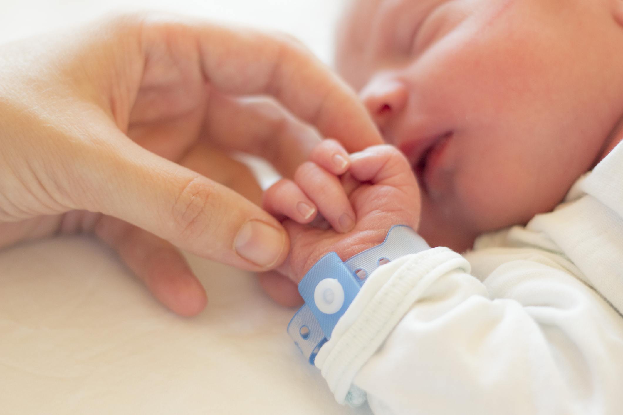 Newborn baby holding a hand