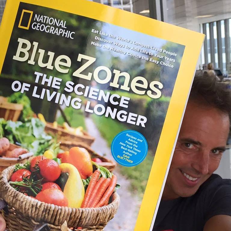 Man holding up a national geographic magazine saying Blue Zones Science of living longer