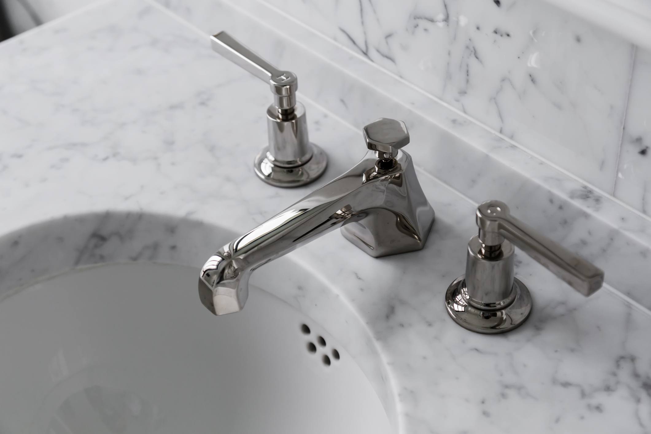 closeup faucet and lavatory white marble restroom interior concept