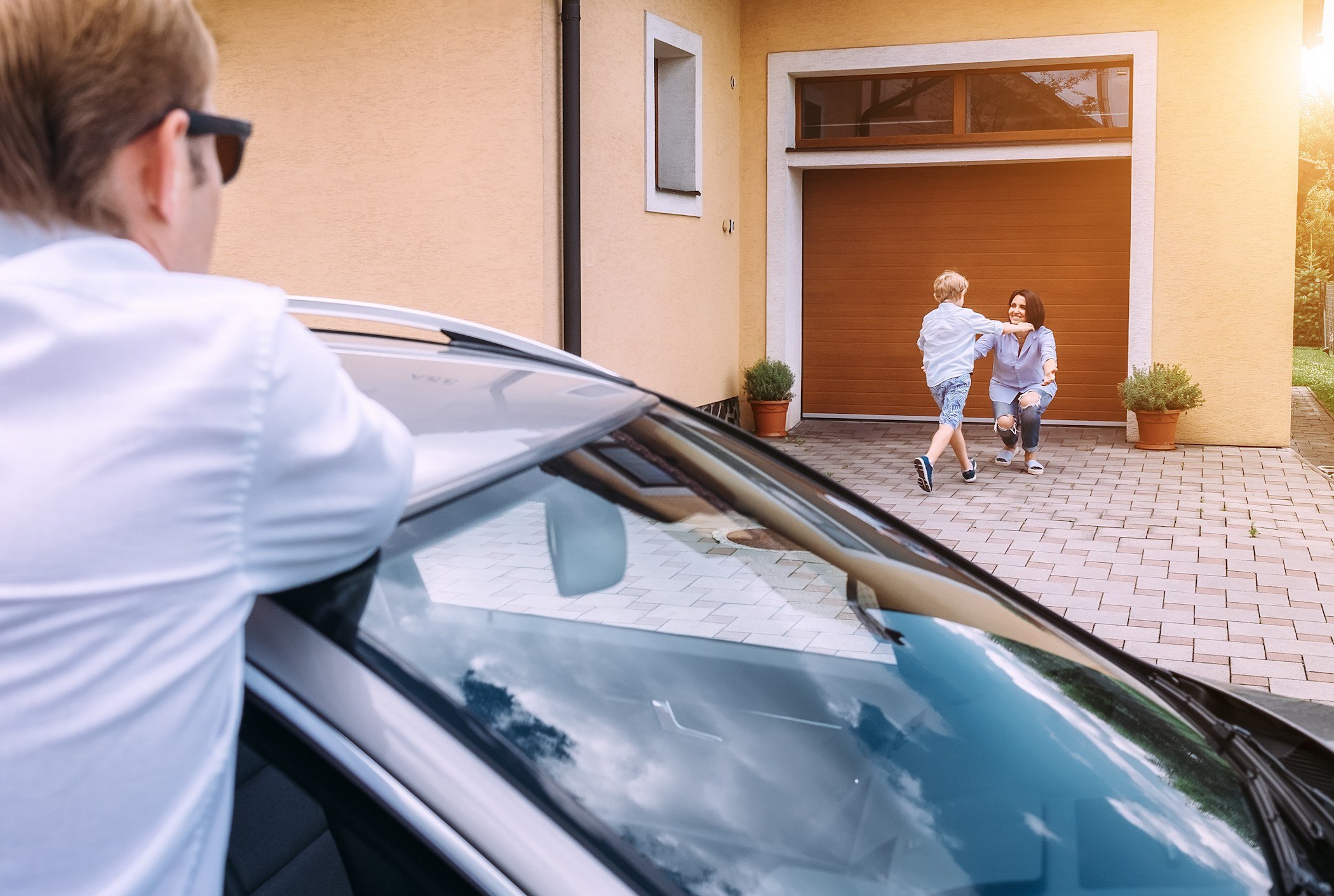 A son runs to his mother while father waits at the car.