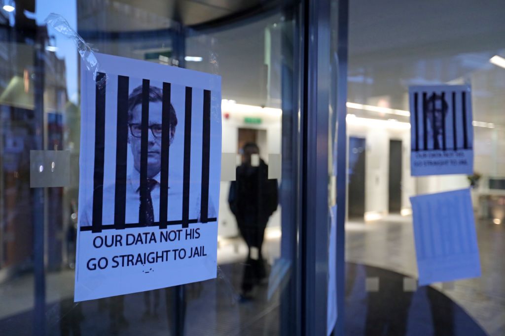 Posters depicting Cambridge Analytica's CEO Alexander Nix behind bars,