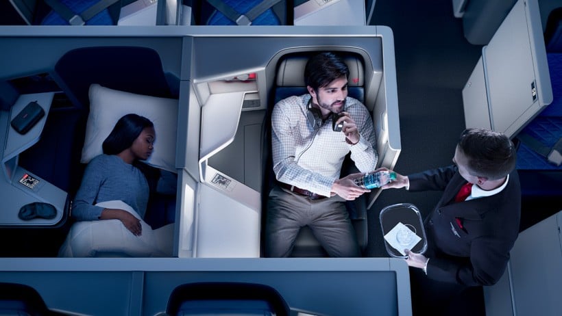 One passenger sleeping and one being given a water bottle on Delta one first class flight