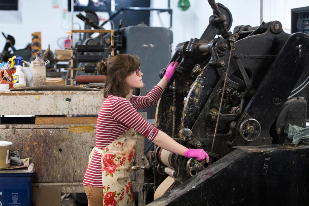 Woman uses the die stamping press at the workshop of Barnard and Westwood