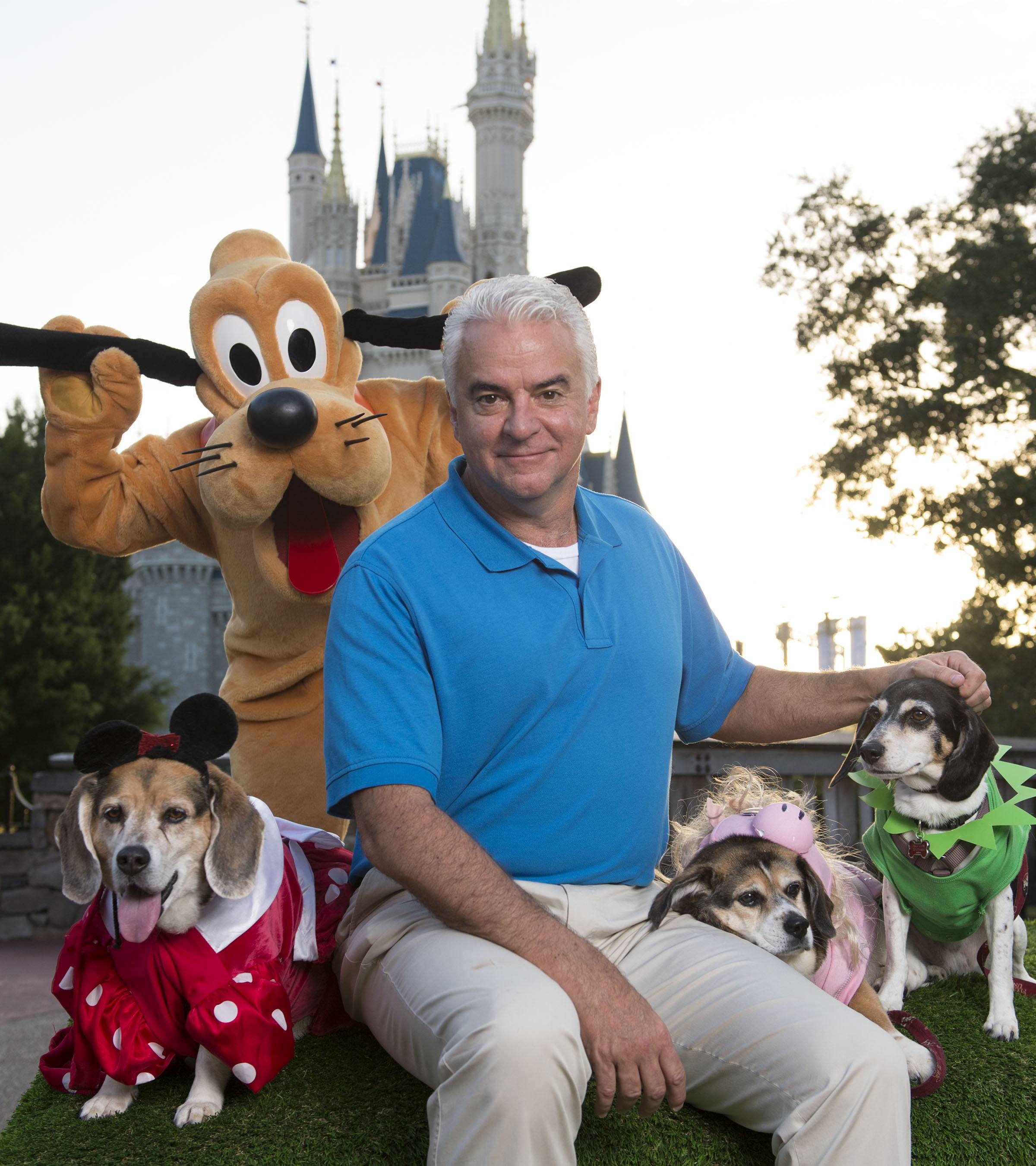 actor John O'Hurley poses with Pluto and three Disney-dressed dogs at the Magic Kingdom at Walt Disney World Resort