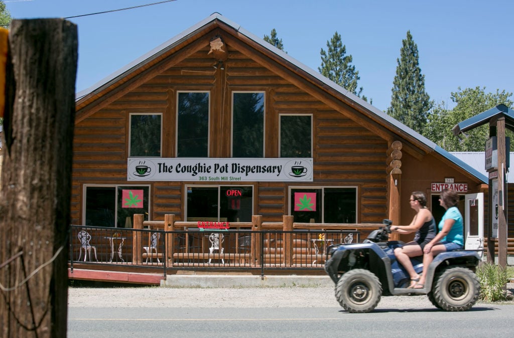 Tourists on a four-wheel leisure vehicle pass the Coughie Pot marijuana dispensary
