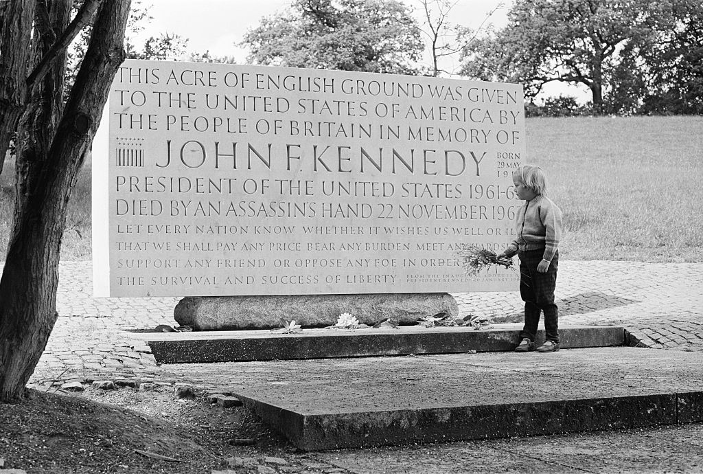 A young girl lays flowers at the John F Kennedy Memorial