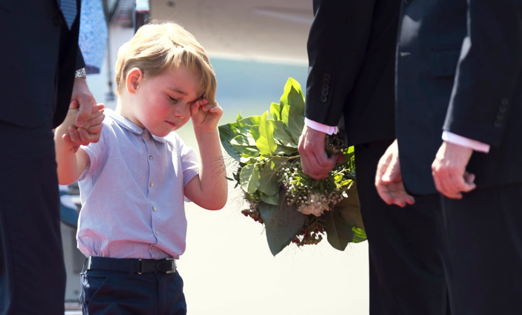 Prince George holds the hand of his father Britain's Prince William Duke of Cambridge, upon their arrival at the airport in Berlin