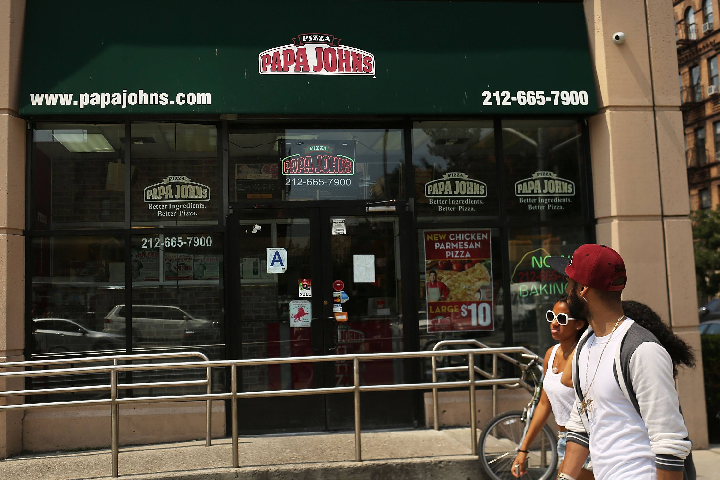 People walk by a Papa Johns pizza restaurant on August 9, 2012 in New York City.