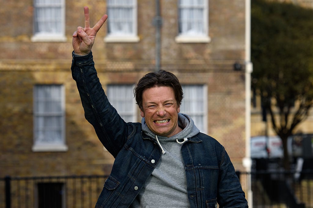 Chef Jamie Oliver smiles and gives a peace sign