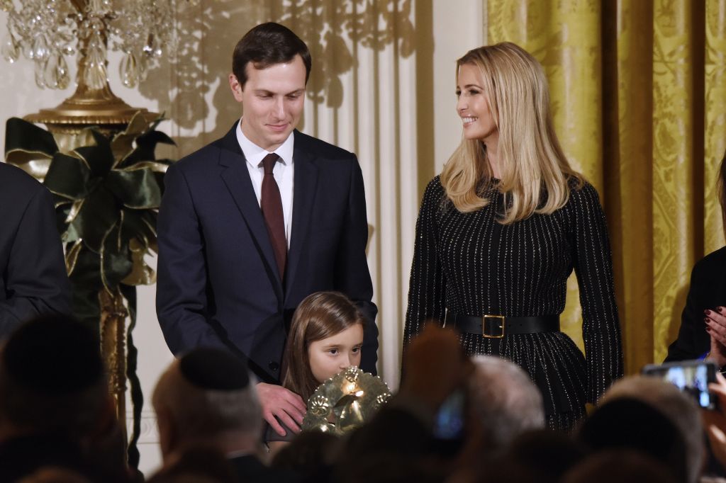 Arabella Kushner lights the menorah as Jared Kushner and Ivanka Trump look on during a Hanukkah Reception