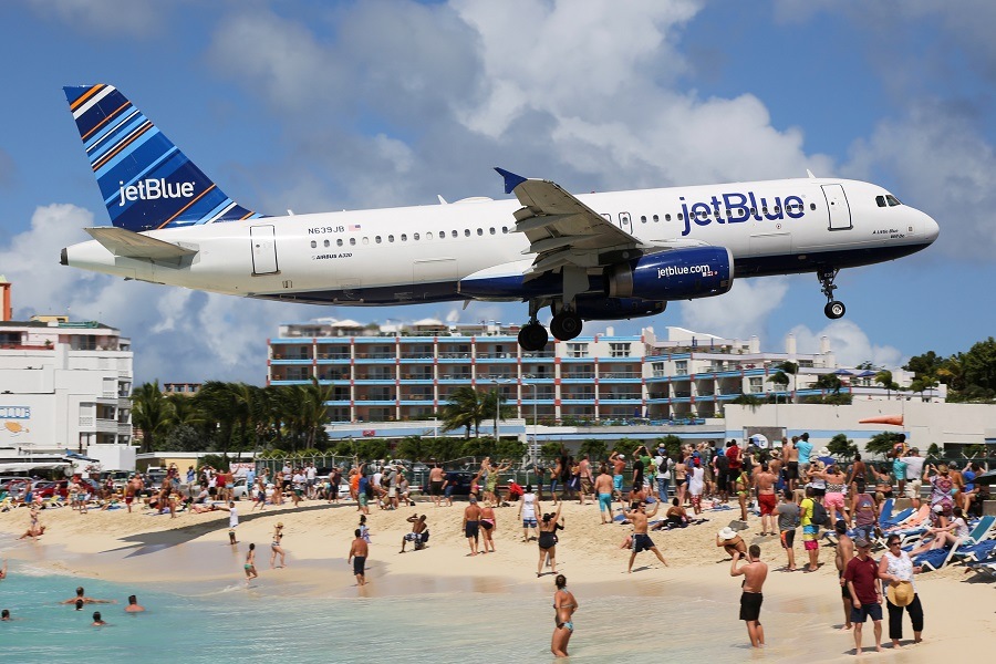 JetBlue plane flying above a beach JetBlue plane flying above a beach