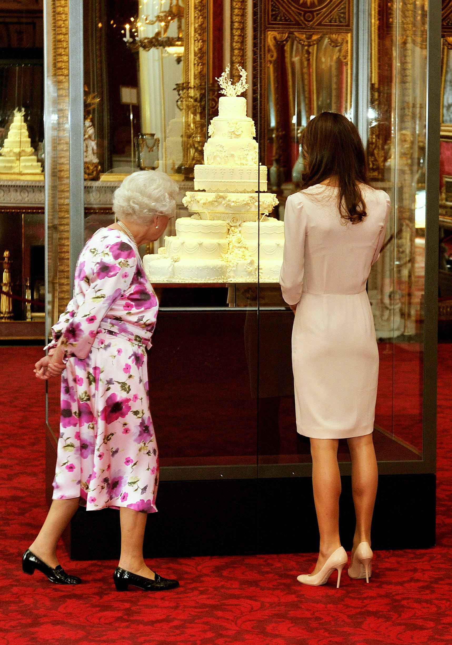 Britain's Queen Elizabeth II (L) and Kate Middleton look at wedding cake in a glass case