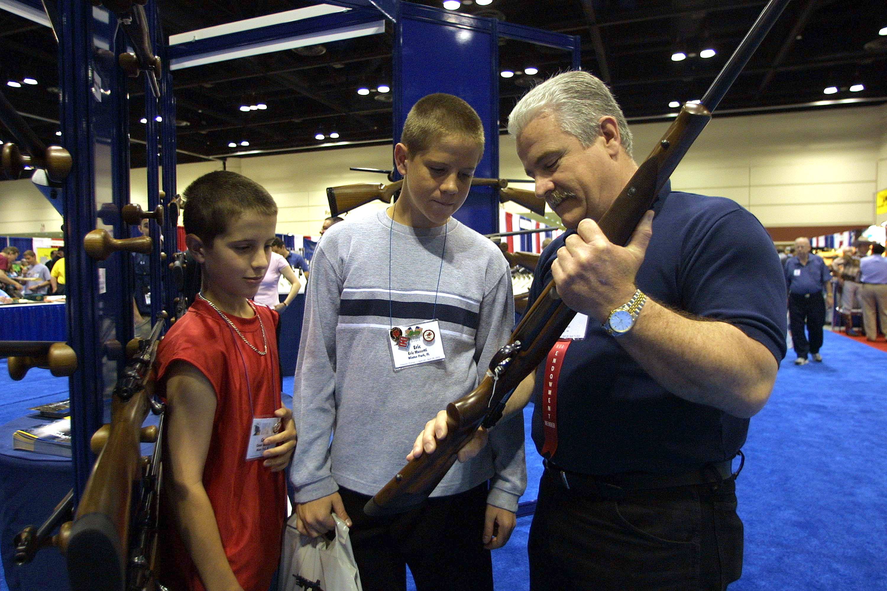 Kids looking at guns at NRA Annual Meeting And Exhibits