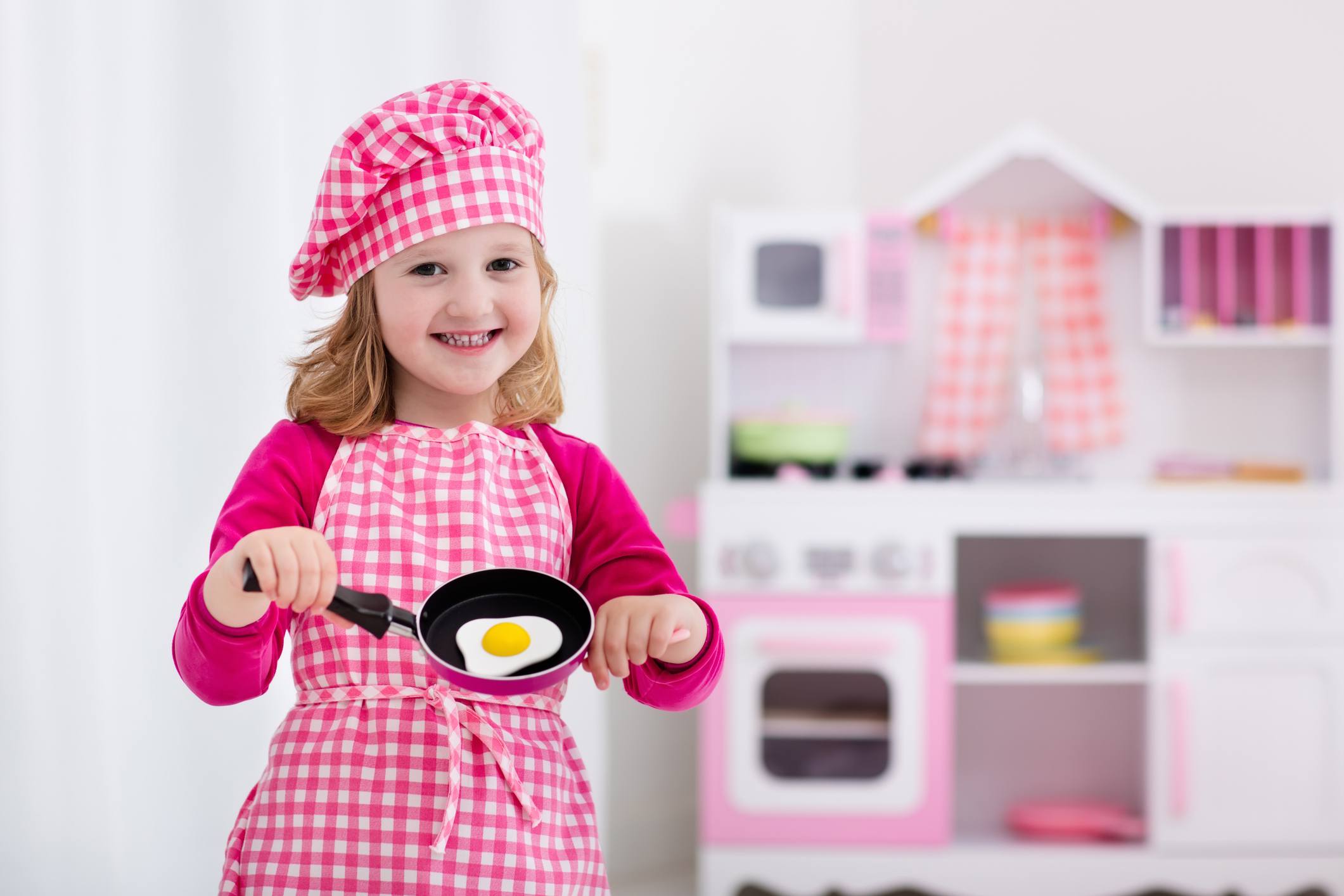 Cute little girl playing with toy kitchen