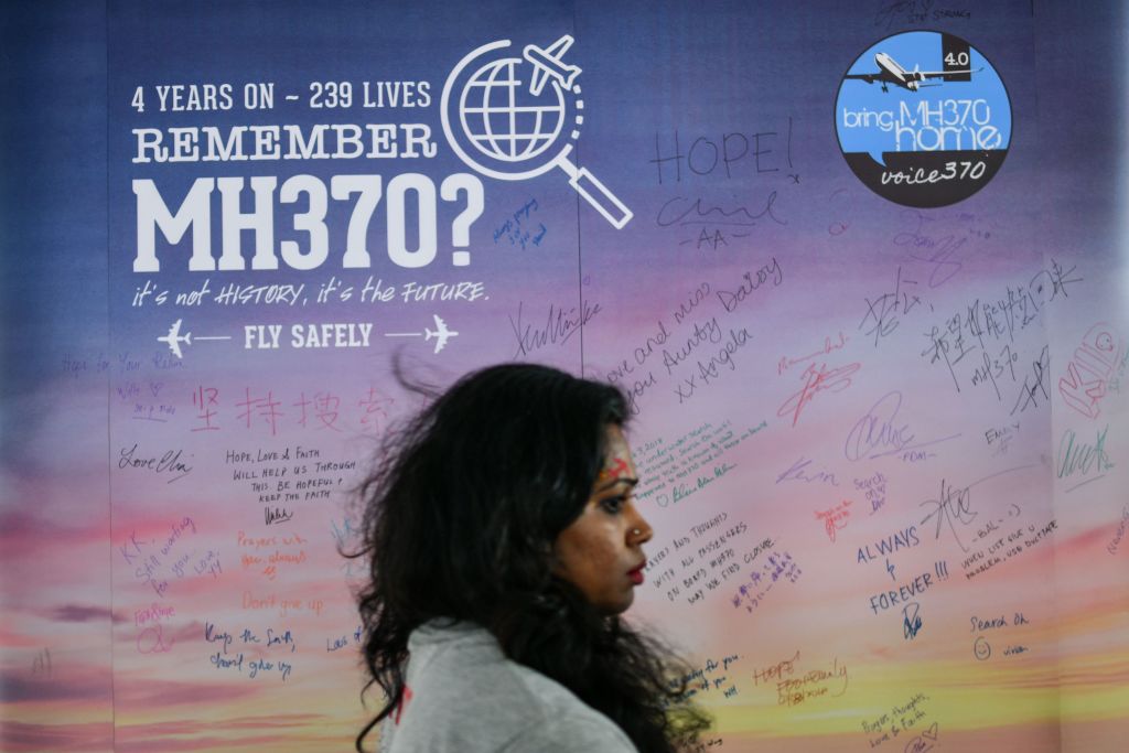 A woman walks past a banner bearing solidarity messages for passengers of the missing Malaysia