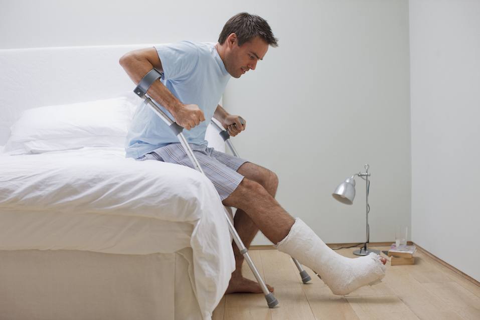 Man with broken leg trying to get up using his crutches