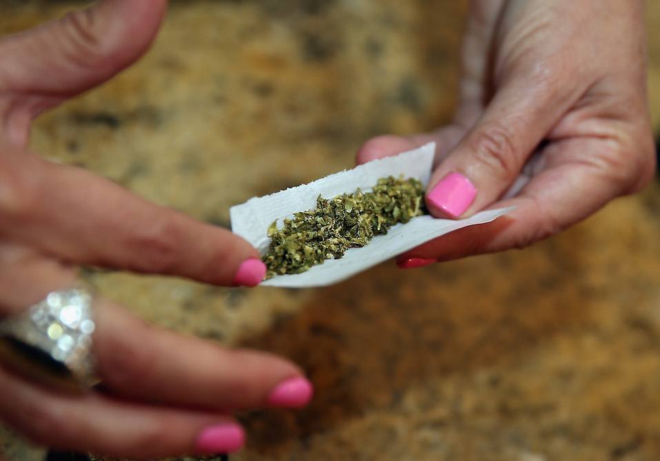 A woman rolls a marijuana cigarette as photographed