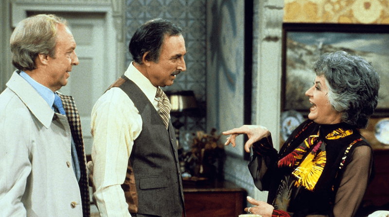Maude speaking with two men inside an apartment. Maude speaking with two men inside an apartment.