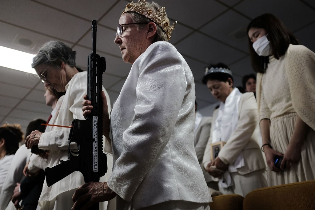 A woman holds an AR-15 rifle during a ceremony at the World Peace and Unification Sanctuary in Newfoundland,