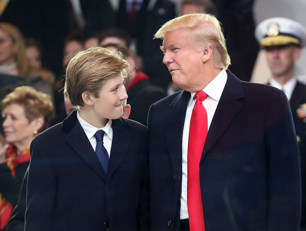 U.S. President Donald Trump stands with his son Barron Trump inside of the inaugural parade reviewing stand in front of the White House