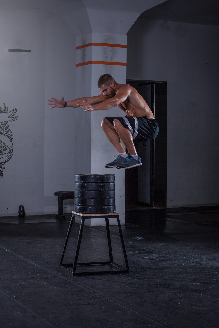 man doing high jumps over weight plates at the gym man doing high jumps over weight plates at the gym