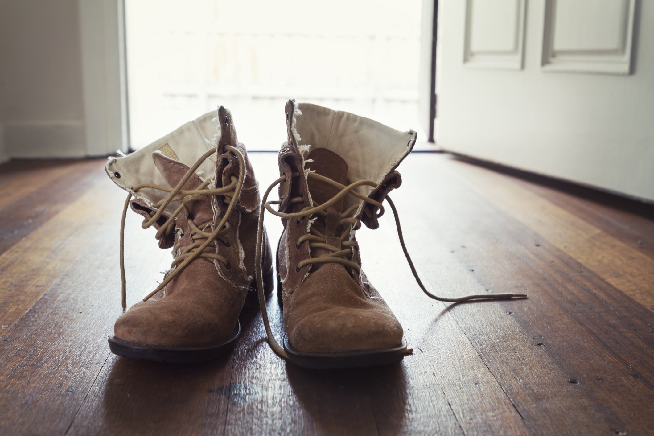 Pair of men's worn leather shoes or boots in doorway of home