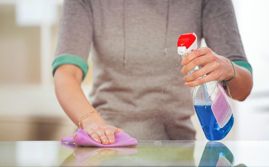 Woman cleans a glass table with a spray