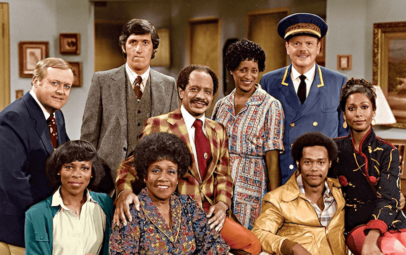 The cast of 'The Jeffersons' standing together in a living room. 