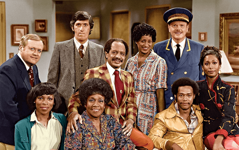 The cast of 'The Jeffersons' standing together in a living room. The cast of 'The Jeffersons' standing together in a living room.