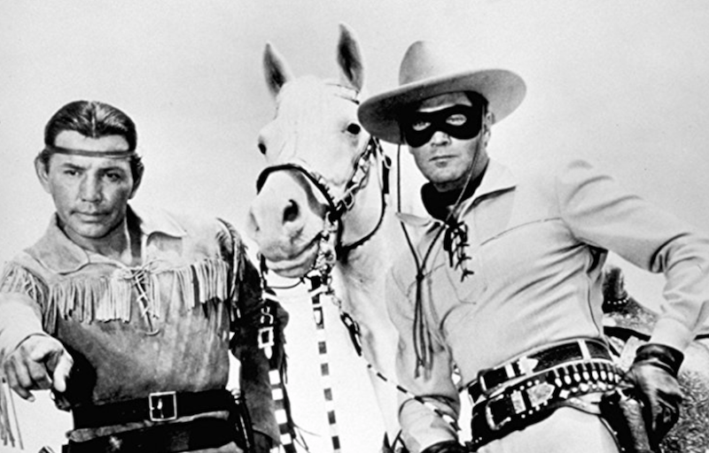 The cowboy and Indian standing with a white horse. 