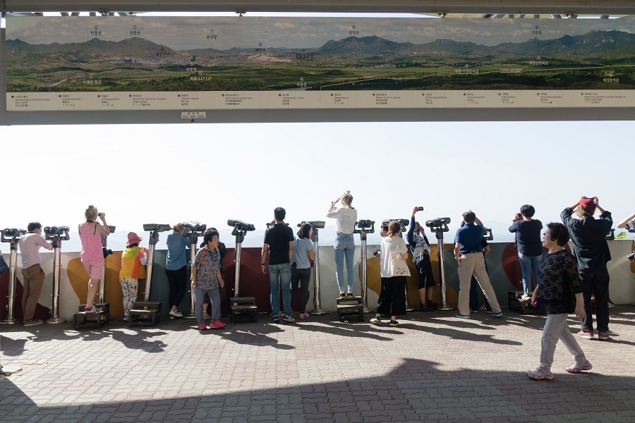 Tourists watching with binoculars to North Korean village Propaganda village or Peace village at Korean Demilitarized Zone