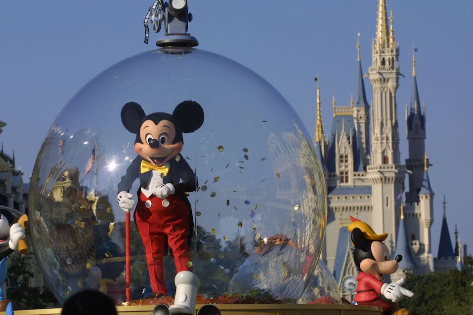 Mickey Mouse rides in a parade through Main Street