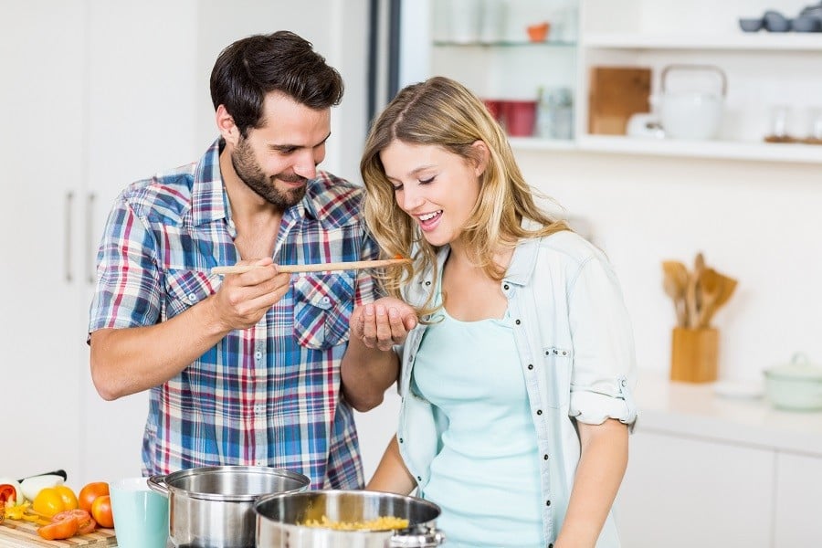 Young couple tasting food in the kitchen Young couple tasting food in the kitchen