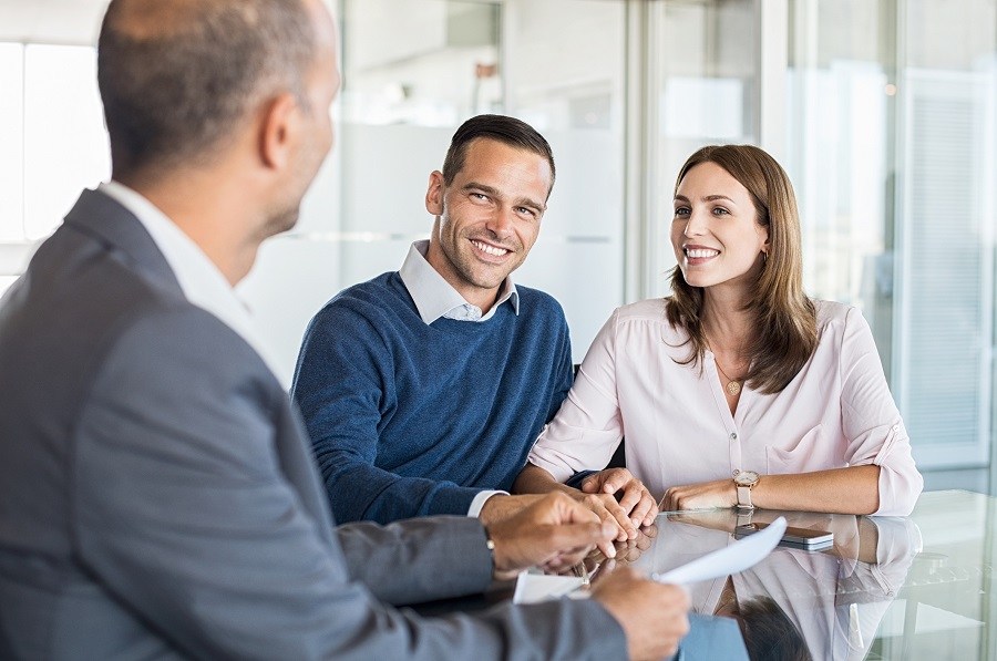 Mature financial advisor showing report to young couple Mature financial advisor showing report to young couple